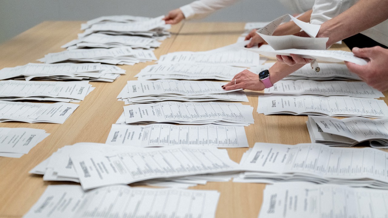 Wahlhelfer sortieren Stimmzettel auf einem Tisch